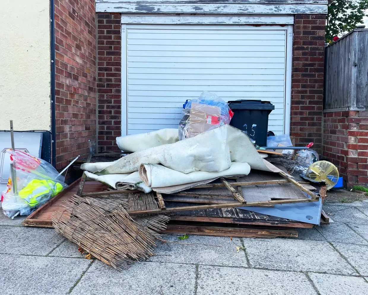 Move-out pile of furniture and debris staged beside a garage for hauling