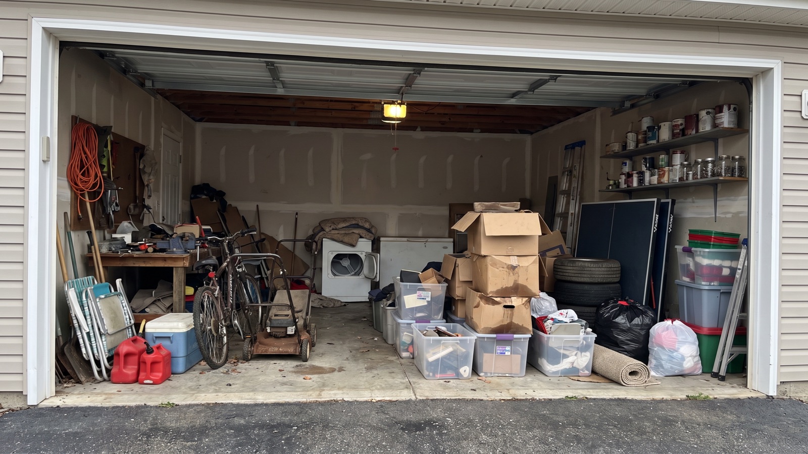 A two-car garage packed wall to wall with boxes, totes, tires and old appliances