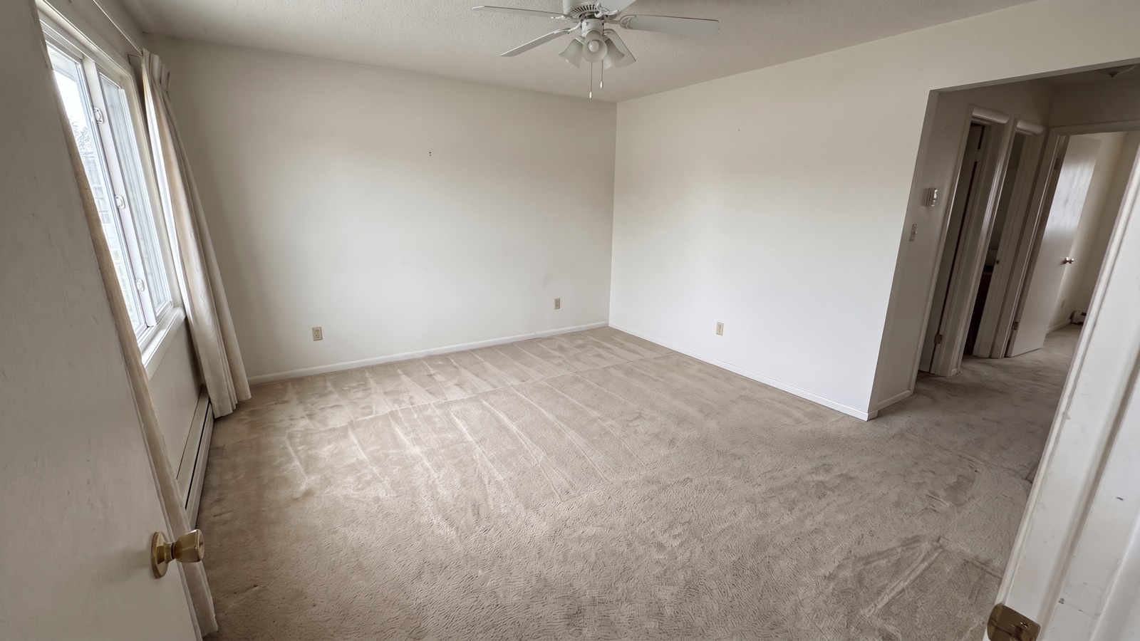 An emptied living room with bare vacuumed carpet after a whole-house cleanout